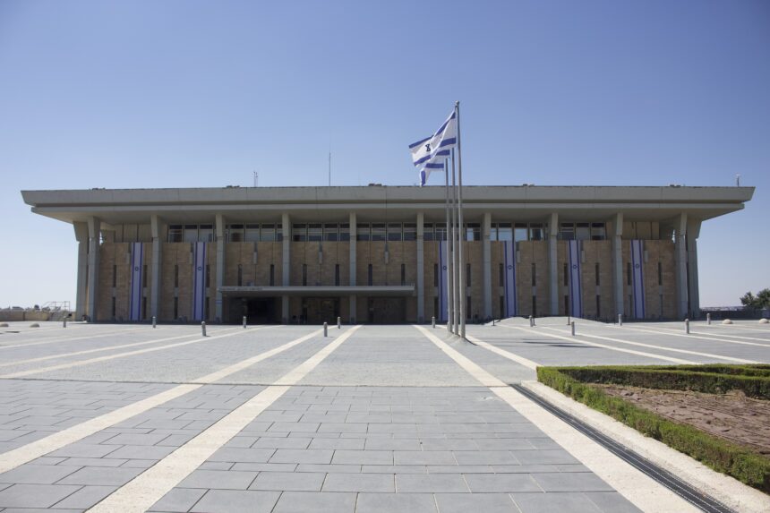 The Knesset parliament building in Jerusalem, Israel, with national flags at the main entrance.