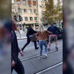 People gathered beside tram tracks during a street confrontation in Belgrade.