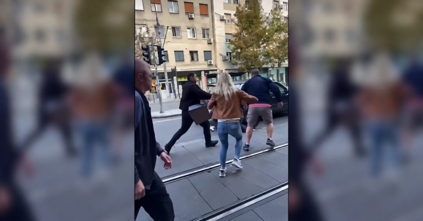 People gathered beside tram tracks during a street confrontation in Belgrade.
